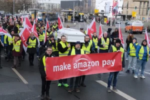 a group of people in yellow vests carrying a coffin and a banner