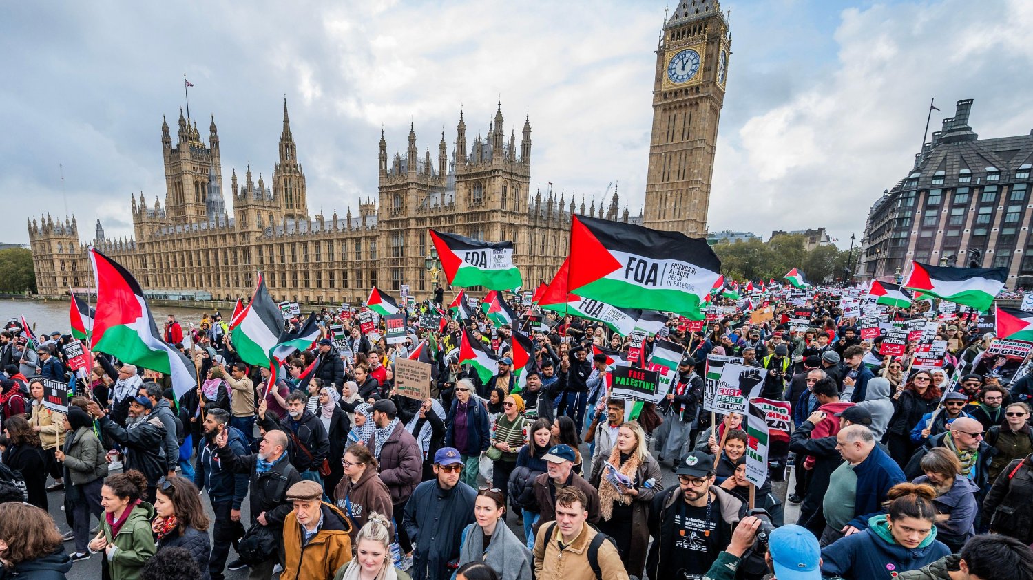 a group of people holding signs and flags in front of a clock tower